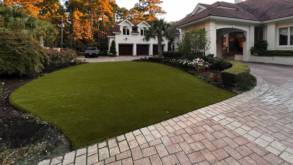 Artificial turf and driveway landscaping with sculpted planting beds